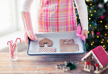 Image showing closeup of woman with gingerbread house on pan