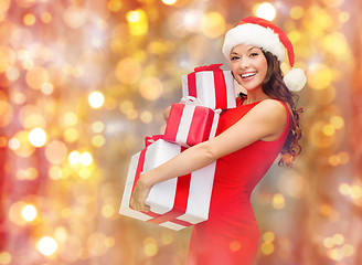 Image showing smiling woman in santa hat holding gift boxes