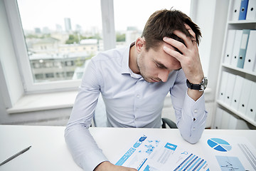 Image showing stressed businessman with papers in office