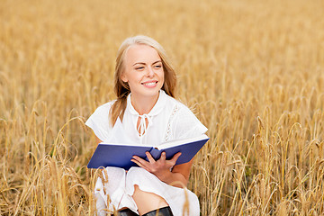 Image showing smiling young woman reading book on cereal field