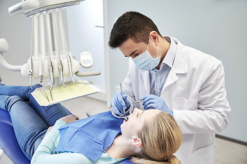 Image showing male dentist in mask checking female patient teeth