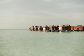 Image showing bungalow huts in sea water on exotic resort beach