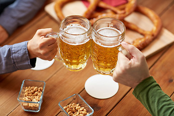 Image showing close up of hands clinking beer mugs at bar or pub