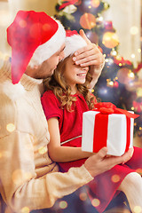 Image showing smiling father surprises daughter with gift box