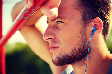 Image showing young man with earphones and horizontal bar