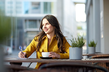 Image showing happy woman with notebook drinking cocoa at cafe