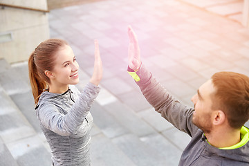 Image showing smiling couple making high five on city street