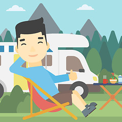 Image showing Man sitting in chair in front of camper van.