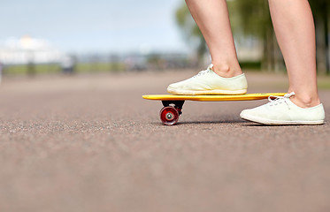 Image showing close up of female feet riding short skateboard