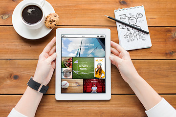 Image showing close up of woman with tablet pc on wooden table