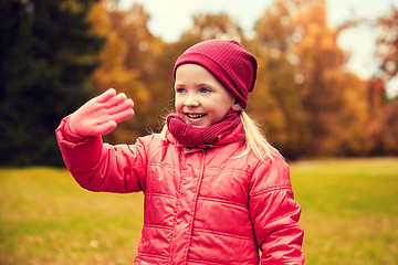 Image showing happy little girl waving hand in autumn park
