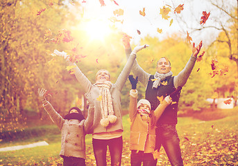 Image showing happy family playing with autumn leaves in park