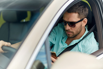 Image showing man in sunglasses driving car with smartphone