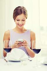 Image showing smiling woman with smartphone at resturant