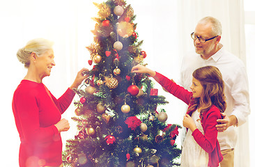 Image showing smiling family decorating christmas tree at home