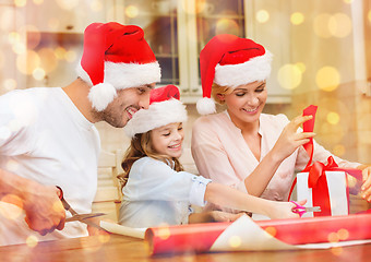 Image showing smiling family in santa helper hats with gift box