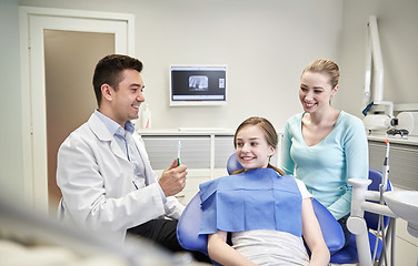 Image showing happy dentist showing toothbrush to patient girl