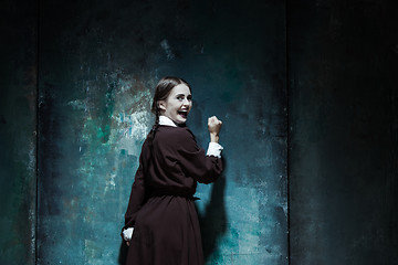 Image showing Portrait of a young smiling girl in school uniform as killer woman