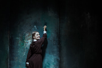 Image showing Portrait of a young smiling girl in school uniform as killer woman