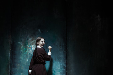 Image showing Portrait of a young smiling girl in school uniform as killer woman