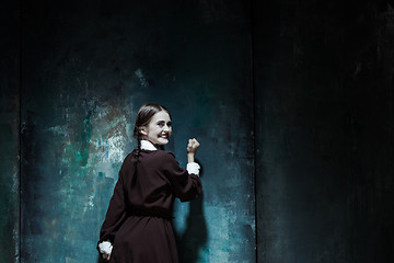 Image showing Portrait of a young smiling girl in school uniform as killer woman