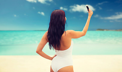 Image showing young woman taking selfie with smartphone on beach