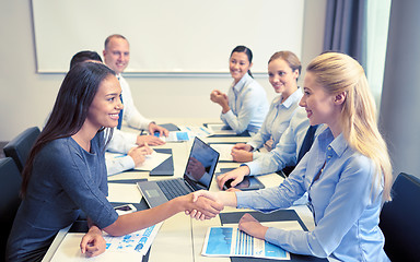 Image showing smiling business people shaking hands in office