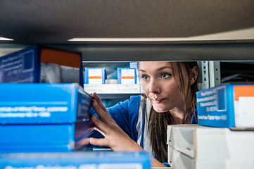 Image showing Mechanic Picking Up Boxes From Storage Rack At Garage