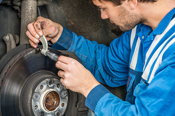Image showing Male Car Mechanic Examining Brake Disc With Caliper