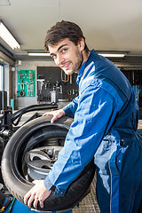 Image showing Confident Mechanic Mounting Car Tire On Rim In Garage