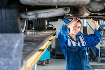 Image showing Female Mechanic Working Under Car On Hydraulic Lift