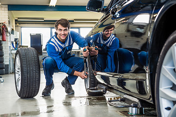 Image showing Confident Mechanic Changing Car Tire In Garage