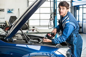 Image showing Male Mechanic Filling Oil Into Car\'s Engine At Garage