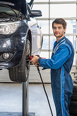 Image showing Male Mechanic Using Pneumatic Wrench To Fix Car Tire