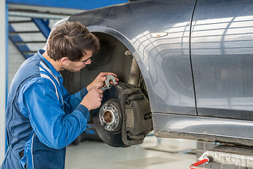 Image showing Car Mechanic Examining Brake Disc With Caliper