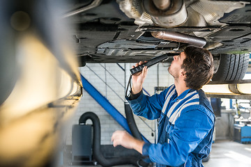 Image showing Mechanic With Flashlight Examining Under The Car