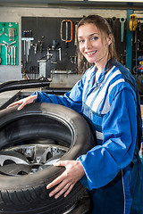 Image showing Smiling Female Mechanic Mounting Car Tire On Rim In Garage