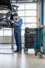 Image showing Mechanic Repairing Brake Of Lifted Automobile At Garage