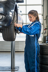 Image showing Female Mechanic Changing Car Tire On Lift At Garage