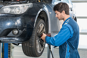 Image showing Mechanic Using Pneumatic Wrench To Fix Car Tire