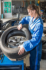 Image showing Female Mechanic Mounting Car Tire On Rim In Garage