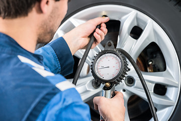 Image showing Mechanic Checking Tire Pressure With Gauge