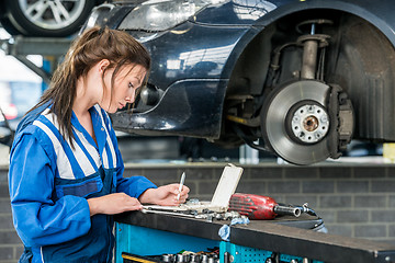 Image showing Young Female Mechanic Making Notes In Garage