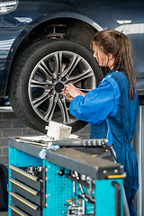 Image showing Mechanic Changing Wheel On Car At Garage