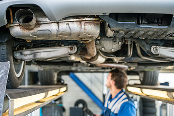 Image showing Car On Hydraulic Lift With Mechanic Working In Garage