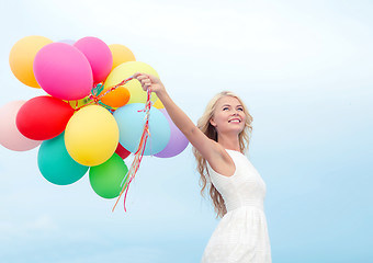 Image showing smiling woman with colorful balloons outside