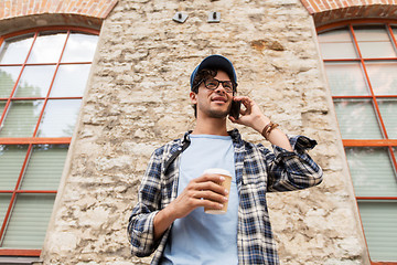 Image showing man with smartphone drinking coffee on city street