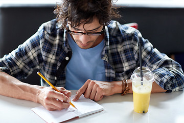 Image showing man with notebook and juice writing at cafe