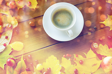 Image showing close up of coffee cup on table with autumn leaves