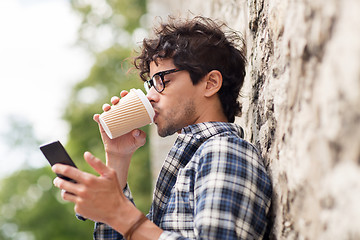 Image showing man with smartphone drinking coffee on city street